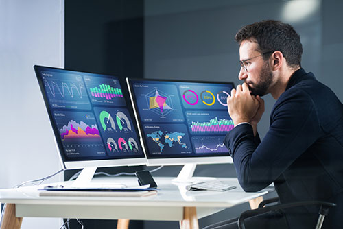 man monitoring dashboards on computer screens