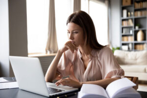 lady looking at laptop with hand on chin